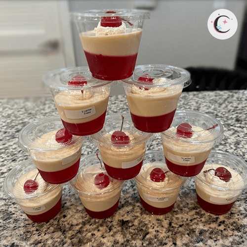 Mini strawberry gelatin with tres leches, topped with whipped cream and a cherry.