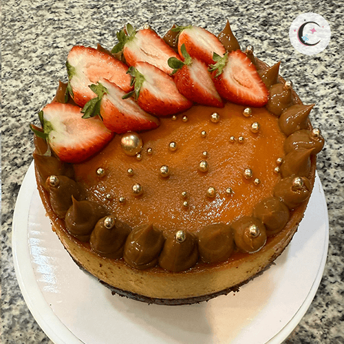 Chocoflan, a chocolate cake topped with flan, decorated with dulce de leche, strawberries, and sugar pearls.