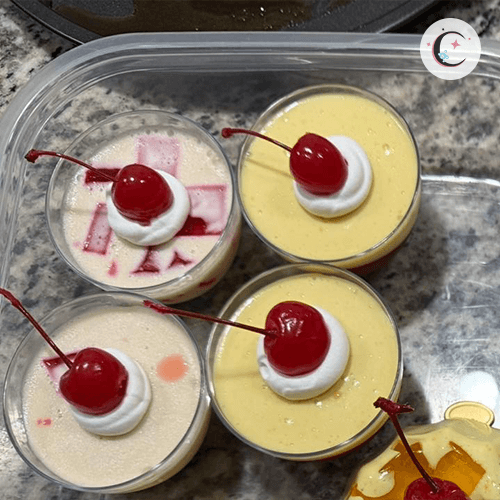 Mini strawberry gelatin with tres leches, topped with whipped cream and a cherry.